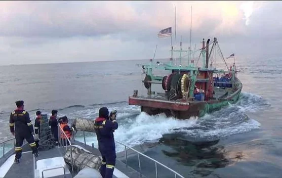 Nelayan dan kapal pengawas di laut sebagai simbol upaya menanggulangi penangkapan ikan ilegal