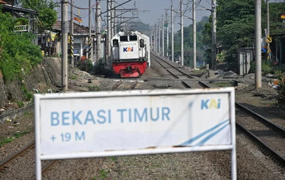 Taksi listrik berhenti di atas rel perlintasan di Bekasi Timur