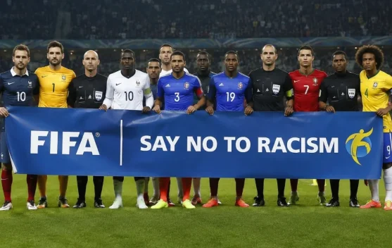 Ilustrasi gestur silang pergelangan tangan 'X' sebagai simbol anti-rasisme di sepak bola