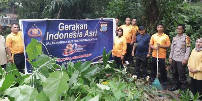 Personel Polres dan petugas kebersihan bekerja gotong royong membersihkan jalan dan saluran air