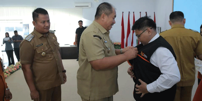 Bupati Asahan menyematkan atribut Sensus Ekonomi 2026 kepada petugas saat acara pelepasan