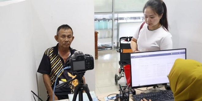 Petugas Imigrasi membantu penyandang disabilitas mengurus paspor di Kantor Imigrasi Belawan