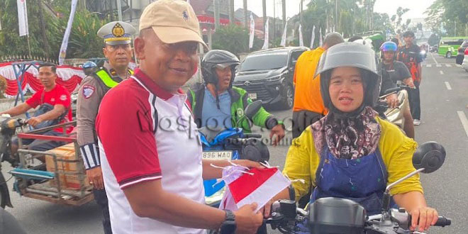 Polisi membagikan bendera merah putih kepada warga di Jalan Merdeka Siantar
