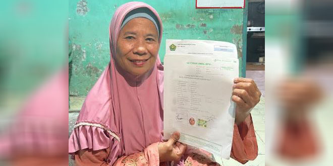 Calon jemaah haji memegang berkas pendaftaran sambil memandang masa depan