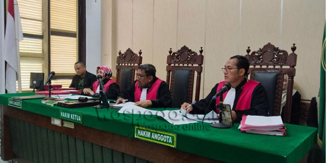 Ilustrasi sidang pengadilan dan laptop sebagai barang bukti kasus penipuan pengadaan
