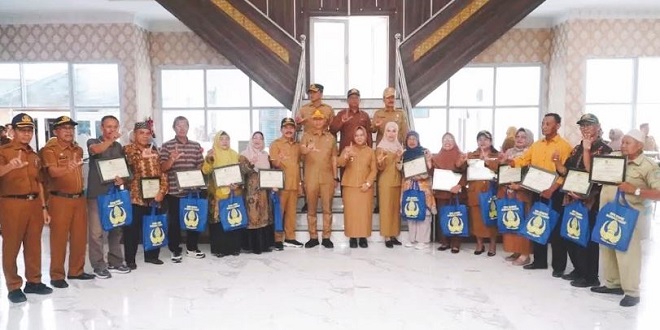 Plt. Bupati Langkat menyerahkan penghargaan kepada ASN purnabakti di lobi kantor bupati Stabat