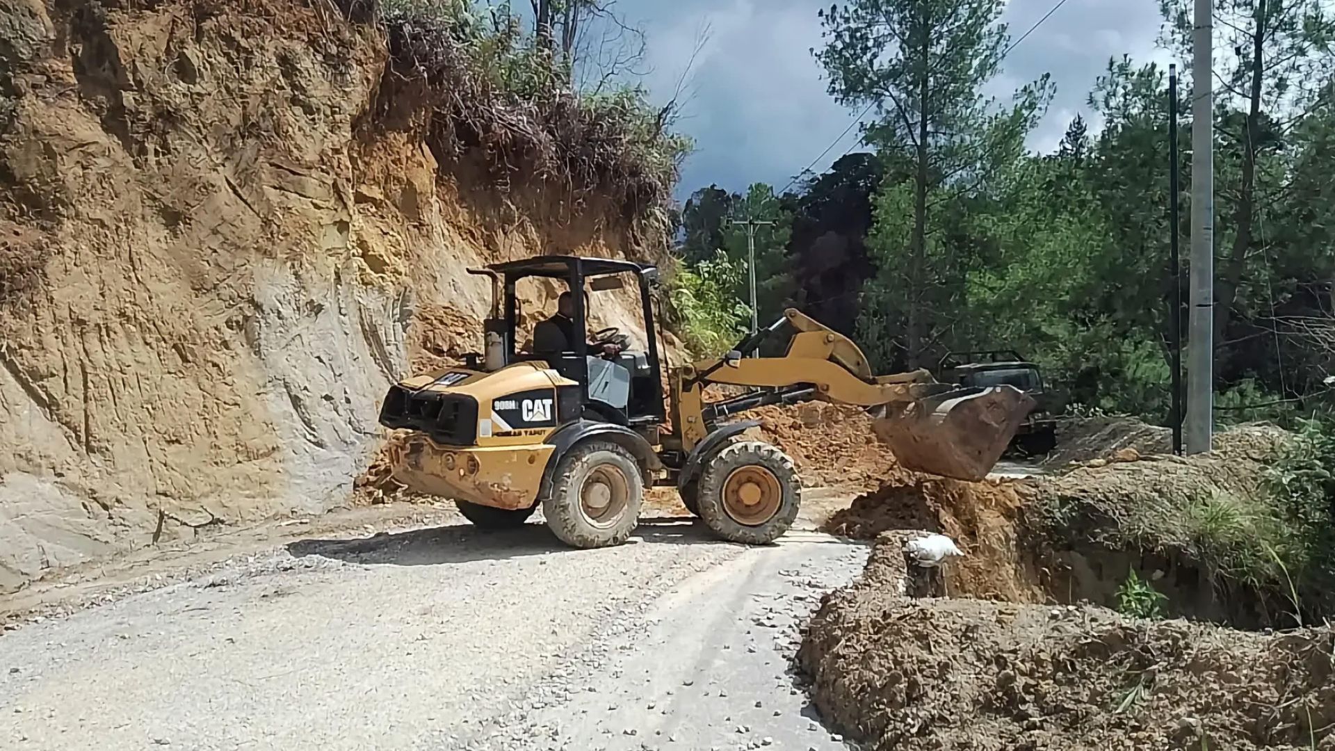 Alat berat wheel loader membersihkan material longsor di jalan Aek Ussim