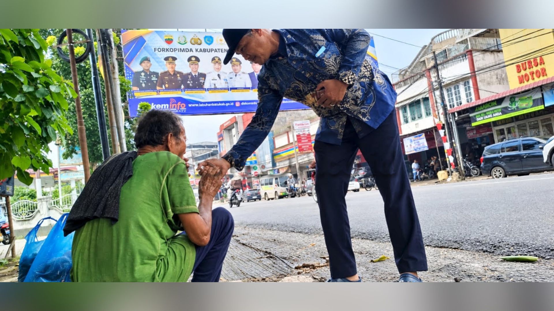 Lansia meminta-minta di tepi Jalan Ahmad Yani dekat baliho HUT ke-81 Pemkab Labuhanbatu