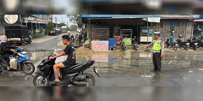 Petugas Sat Lantas meninjau jalan rusak di Jl. Patuan Nagari depan Mapolsek Siantar Utara