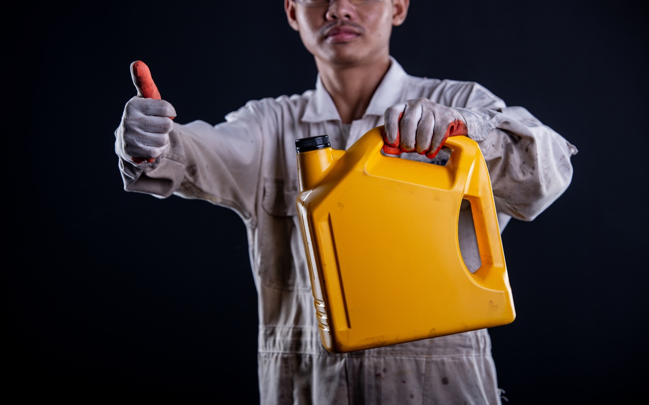 Botol oli motor matic di atas meja bengkel dengan latar peralatan
