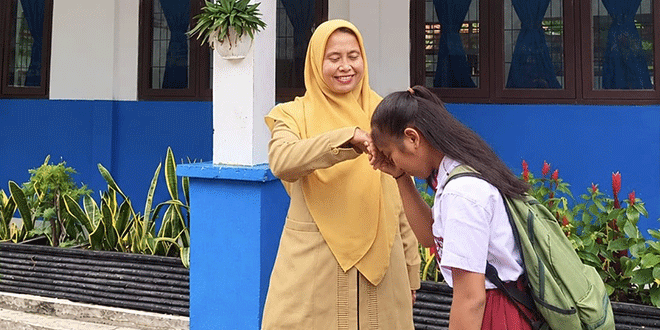 Guru mendampingi murid dalam kelas sambil menjelaskan etika penggunaan media sosial